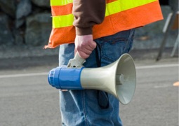 Person wearing a reflective vest holding a bullhorn.