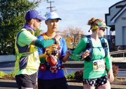 Visually Impaired runner and two guides drinking water during a race.