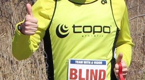 Visually impaired runner Kyle Robidoux giving a thumbs up wearing a blind bib.