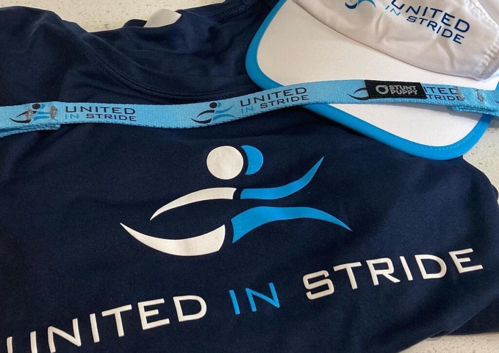 United In Stride printed tshirt, running hat, and handheld tether.