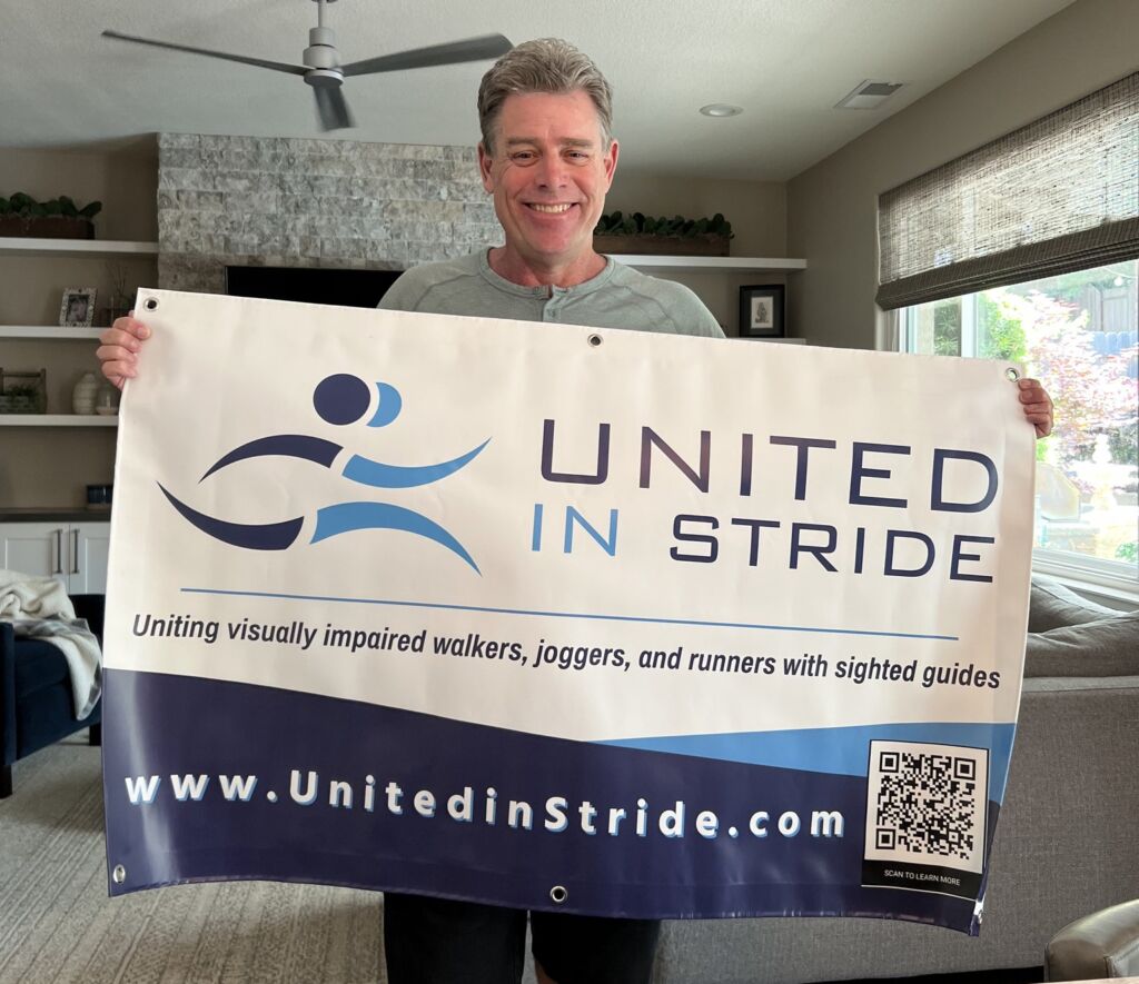 United In Stride founder Richard Hunter holding up a new United In Stride banner.
