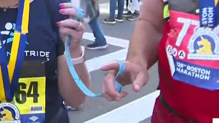 Two runners connected by a tether during the Boston Marathon